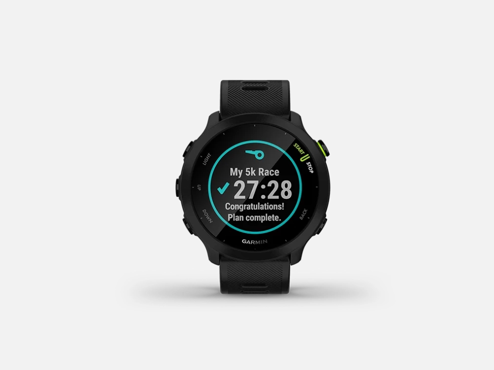 Smartwatch Garmin Forerunner 55 preto exibindo na tela a mensagem de plano de corrida de 5 km concluído com sucesso, com o tempo de 27 minutos e 28 segundos.