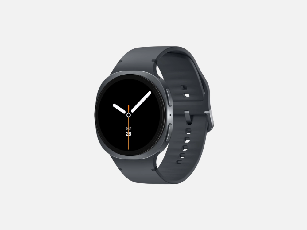 Imagem em fundo cinza do Samsung Galaxy Watch 8 na cor grafite. Este smartwatch para corrida exibe um mostrador circular minimalista escuro com ponteiros analógicos e a data "SAT 28", acompanhado por uma pulseira lisa de silicone cinza.